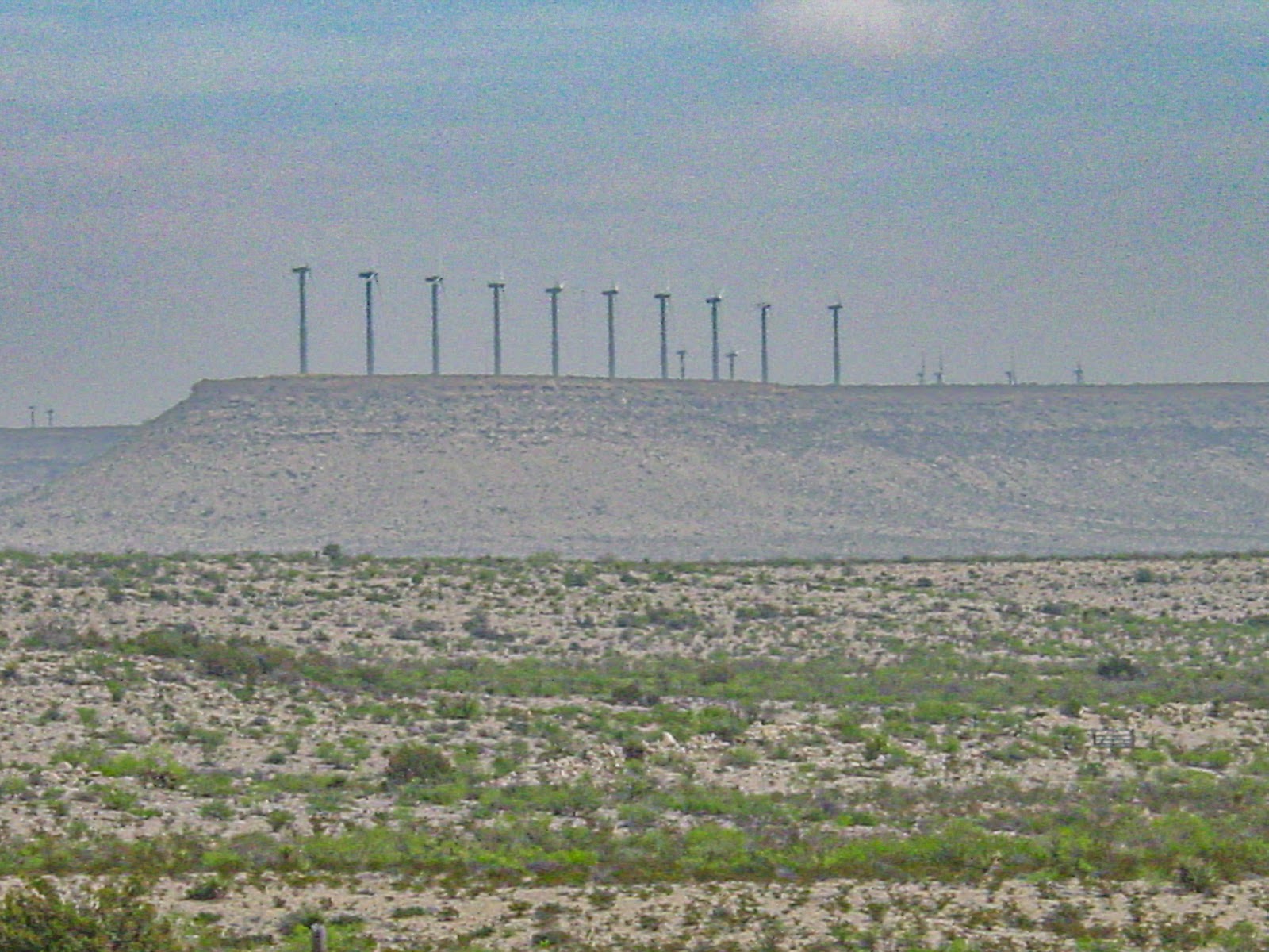 Row of windmills on a distant mesa with a pale blue sky