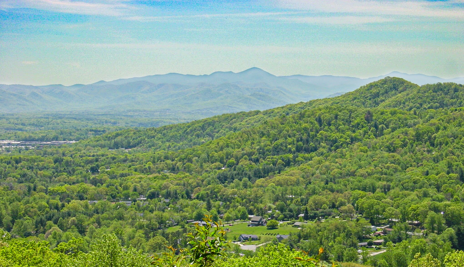 Sharp tall mountains in the background of hills and a valley home. 