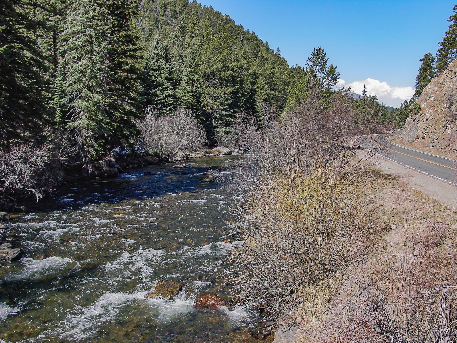 A stream runs over rocks with a road beside it. 
