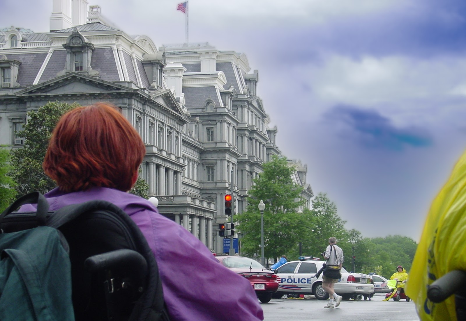 A Victorian four-story building has a woman using a wheelchair in the foreground. 
