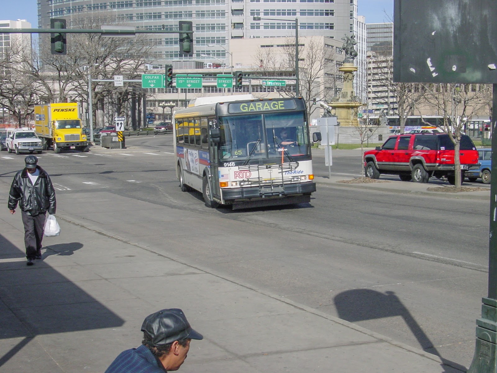 Bus turning past people in downtown. 