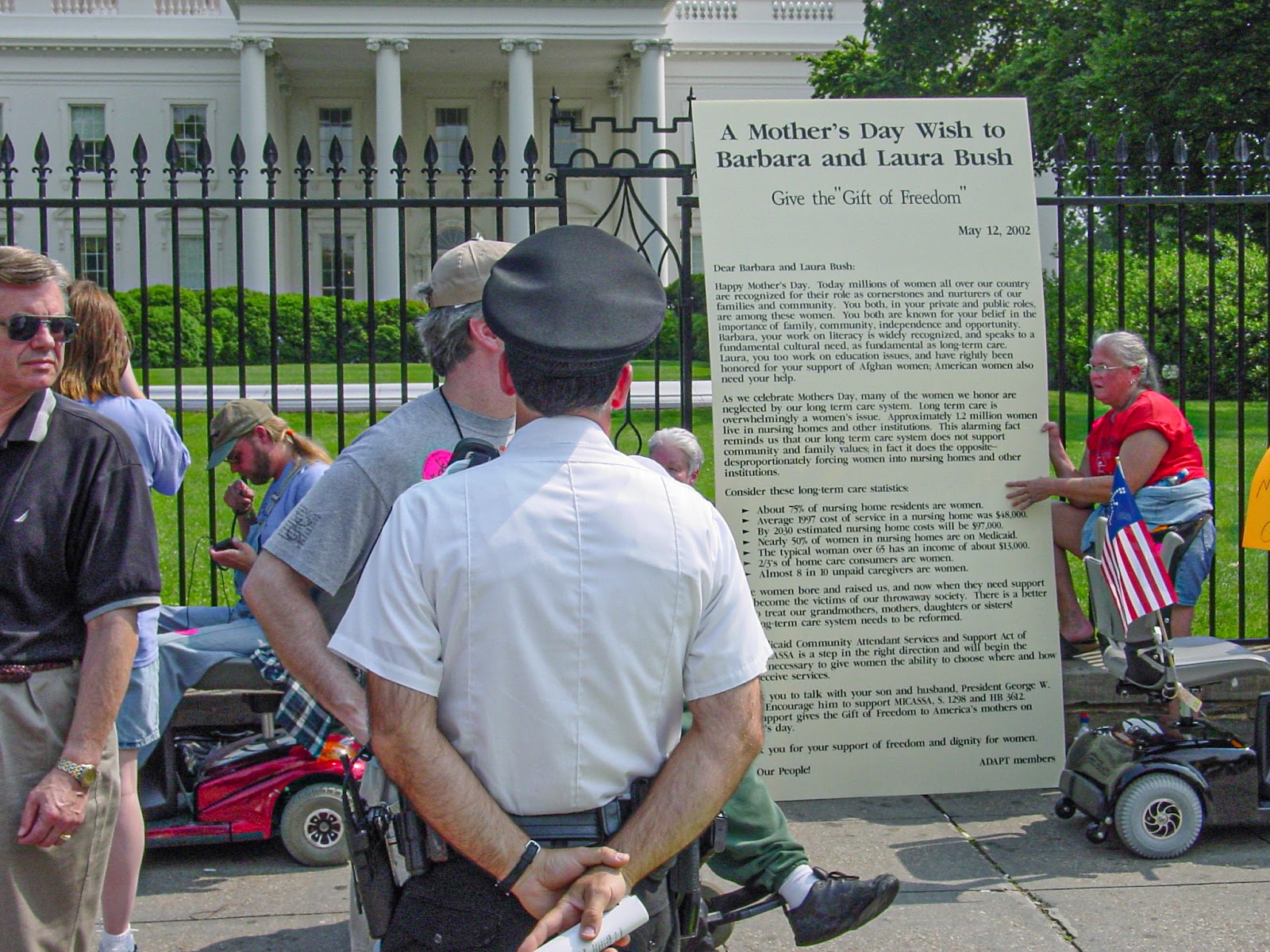 People using wheelchairs place a huge letter on the fence of the White House while park police look on. 