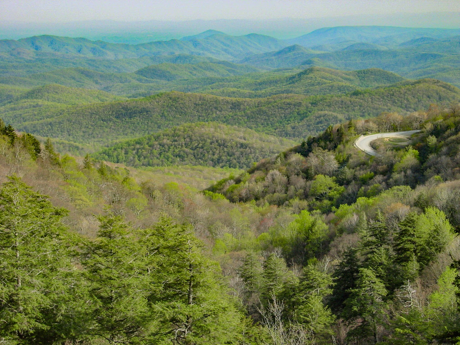 The scene looks down into a mountain valley with a road snaking up on the right. 