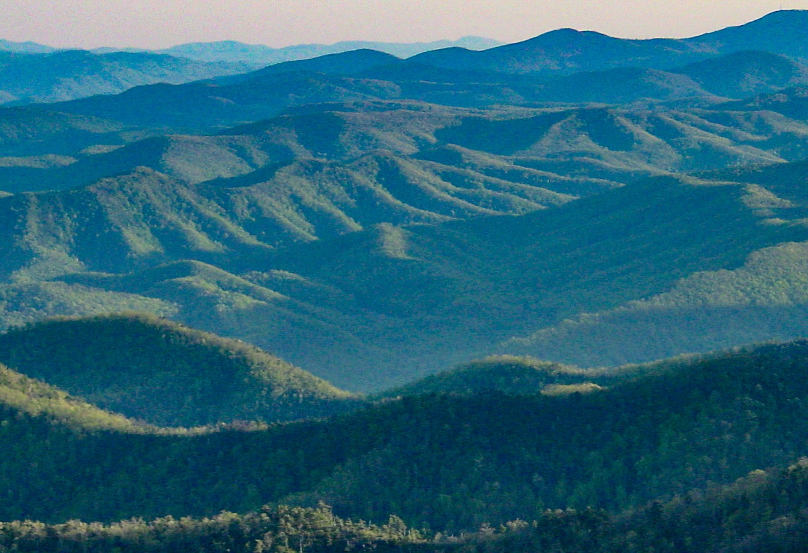 Green foreground mountains  and contour fade into the distant horizon. 