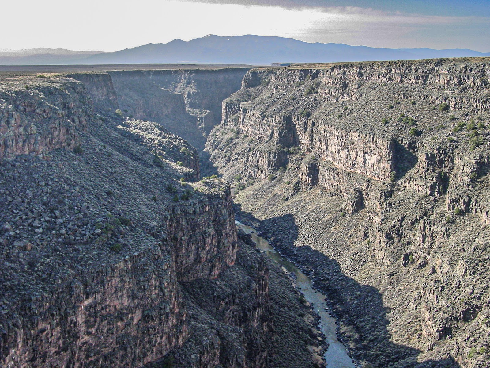 A river flows hundreds of feet below the rim of a steep gorge. 