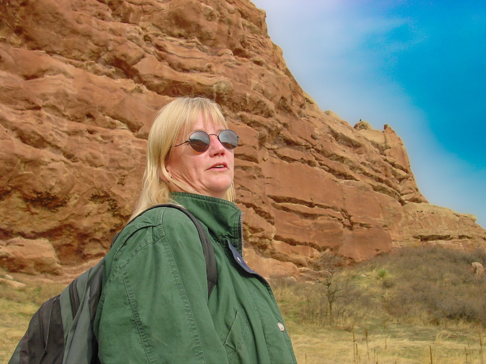 Woman in sunglasses with huge reddish rocks in the background.