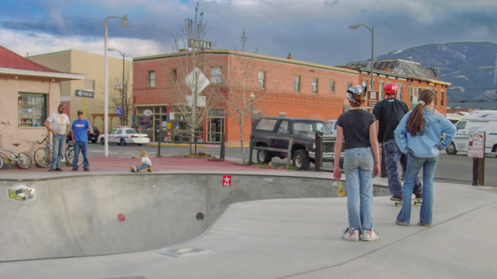 Young people standing around the edge of a skatepark. 