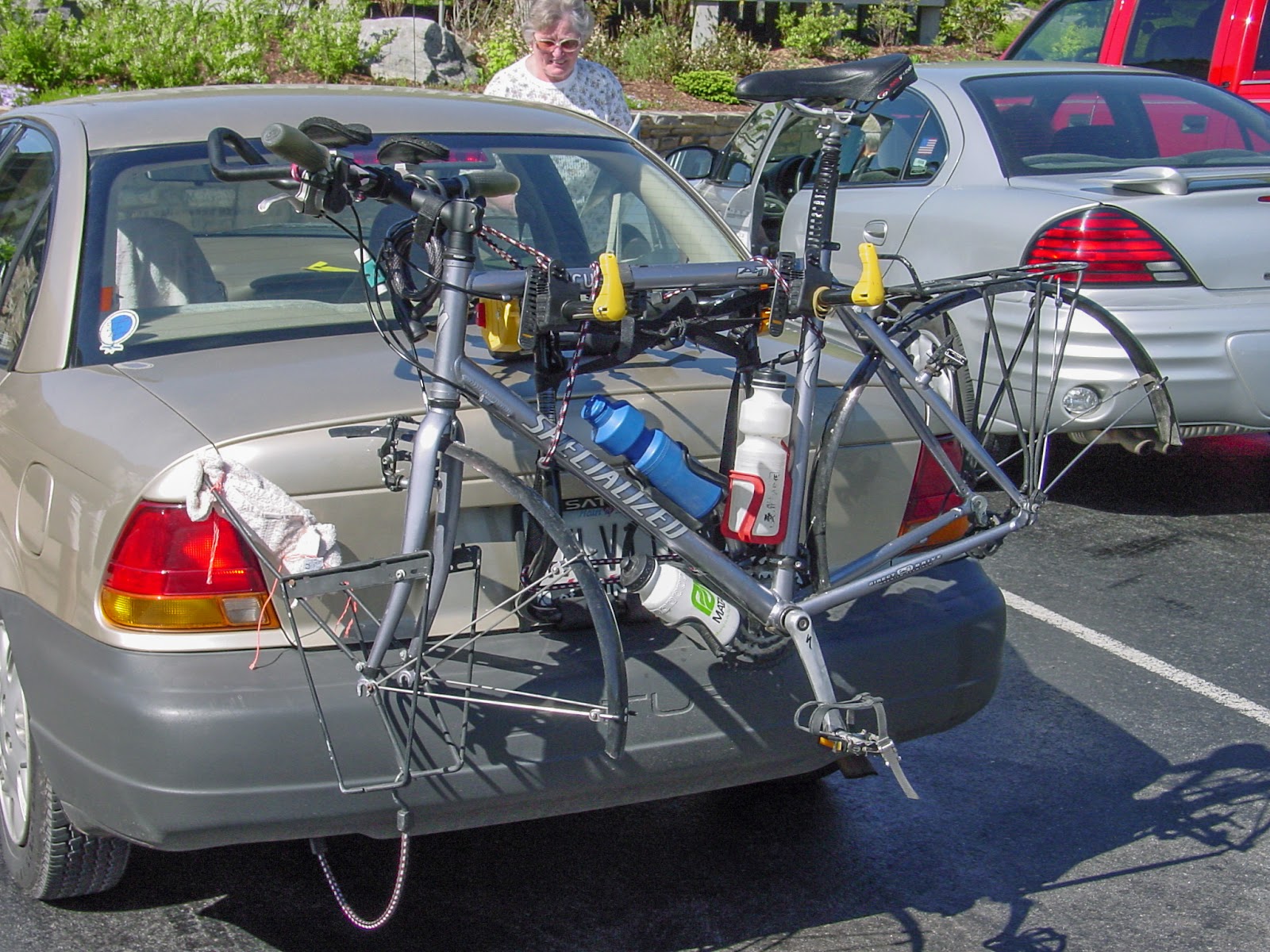 A bike with wheels removed is on a rack on the back of a car. 