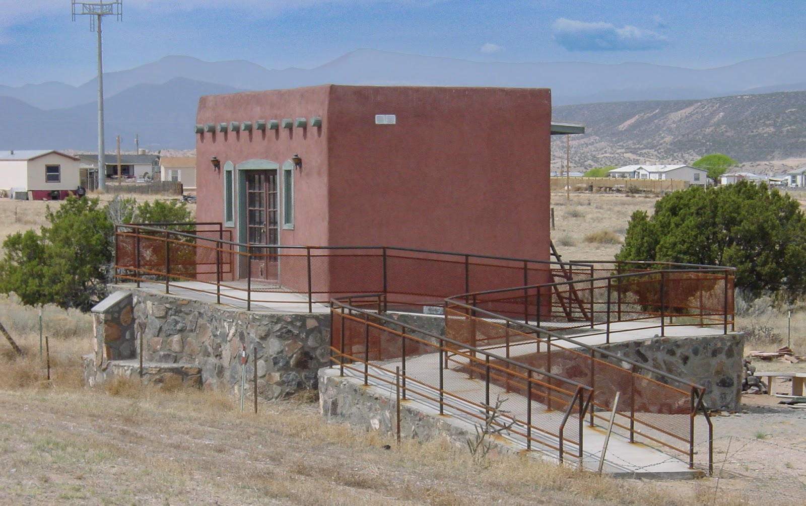 A long ramp is nearly as big as the building it serves. High Mountains are in the background. 