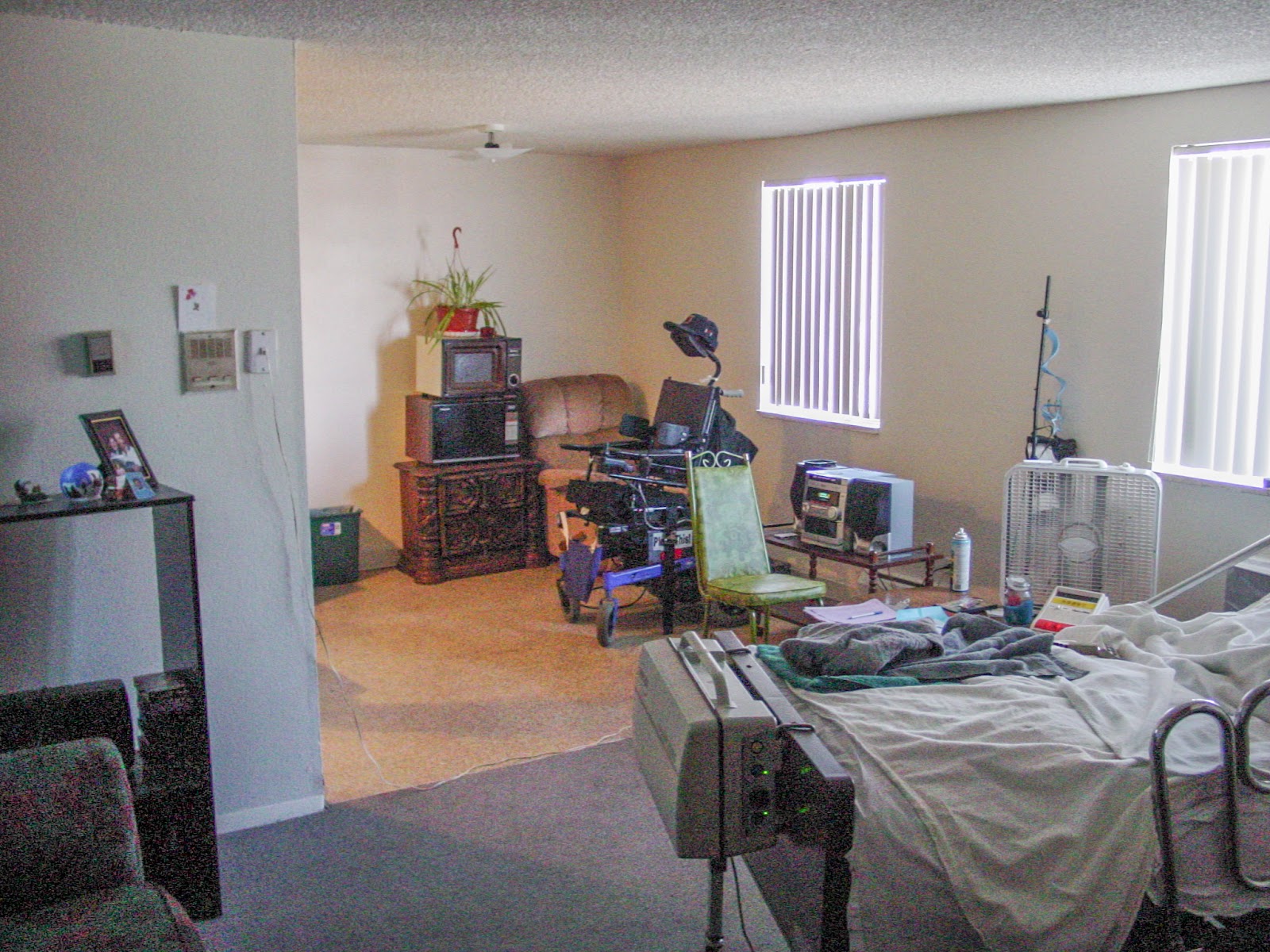 A plain apartment with unmade bed and power wheelchair.