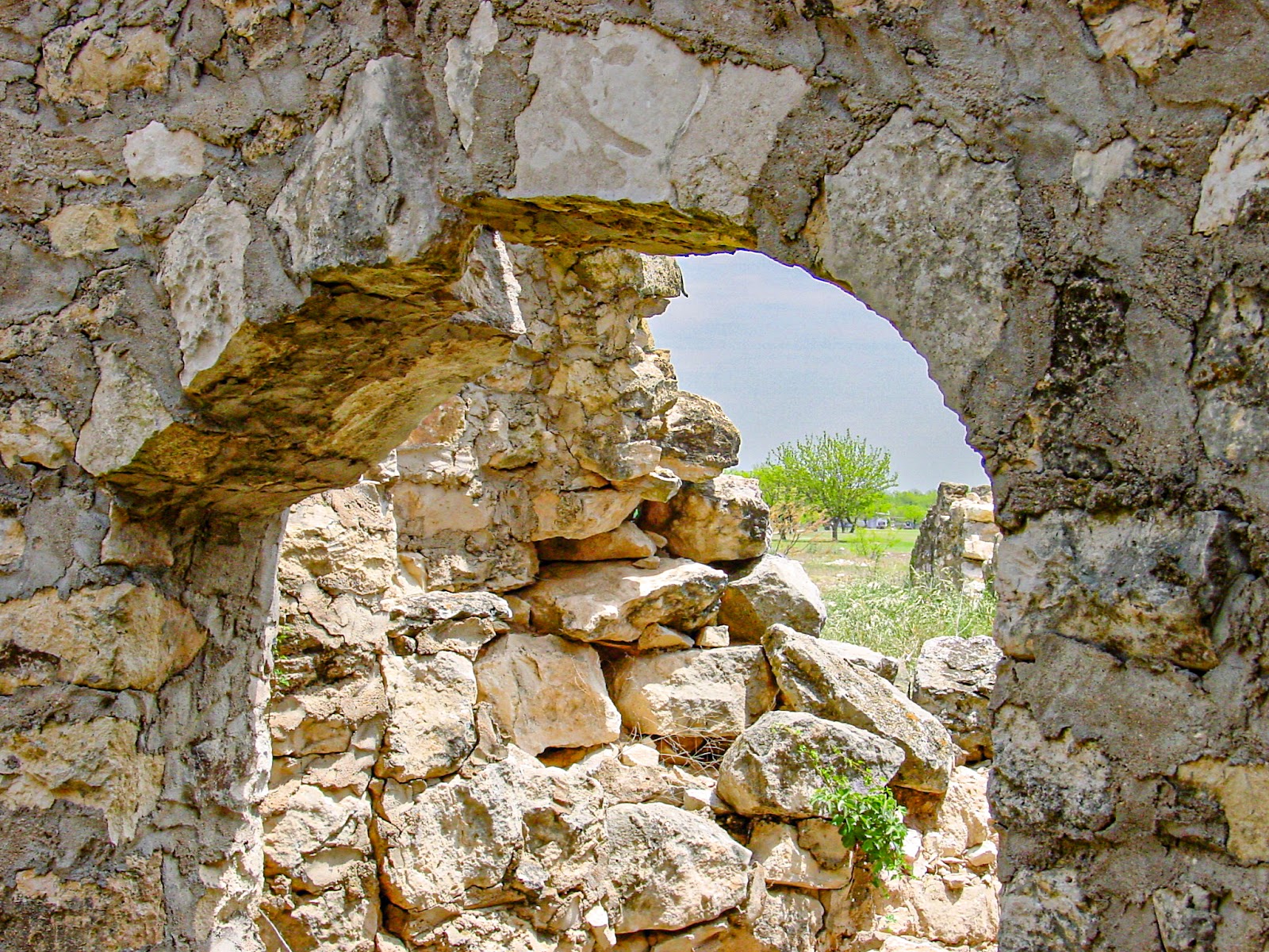 A view through an arched window of an old fieldstone structure.