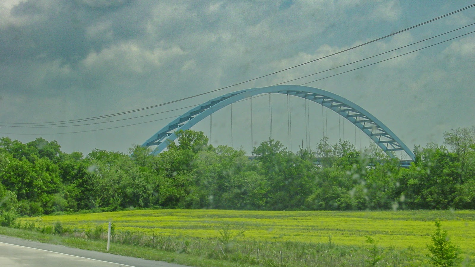 An arched bridge behind trees. 