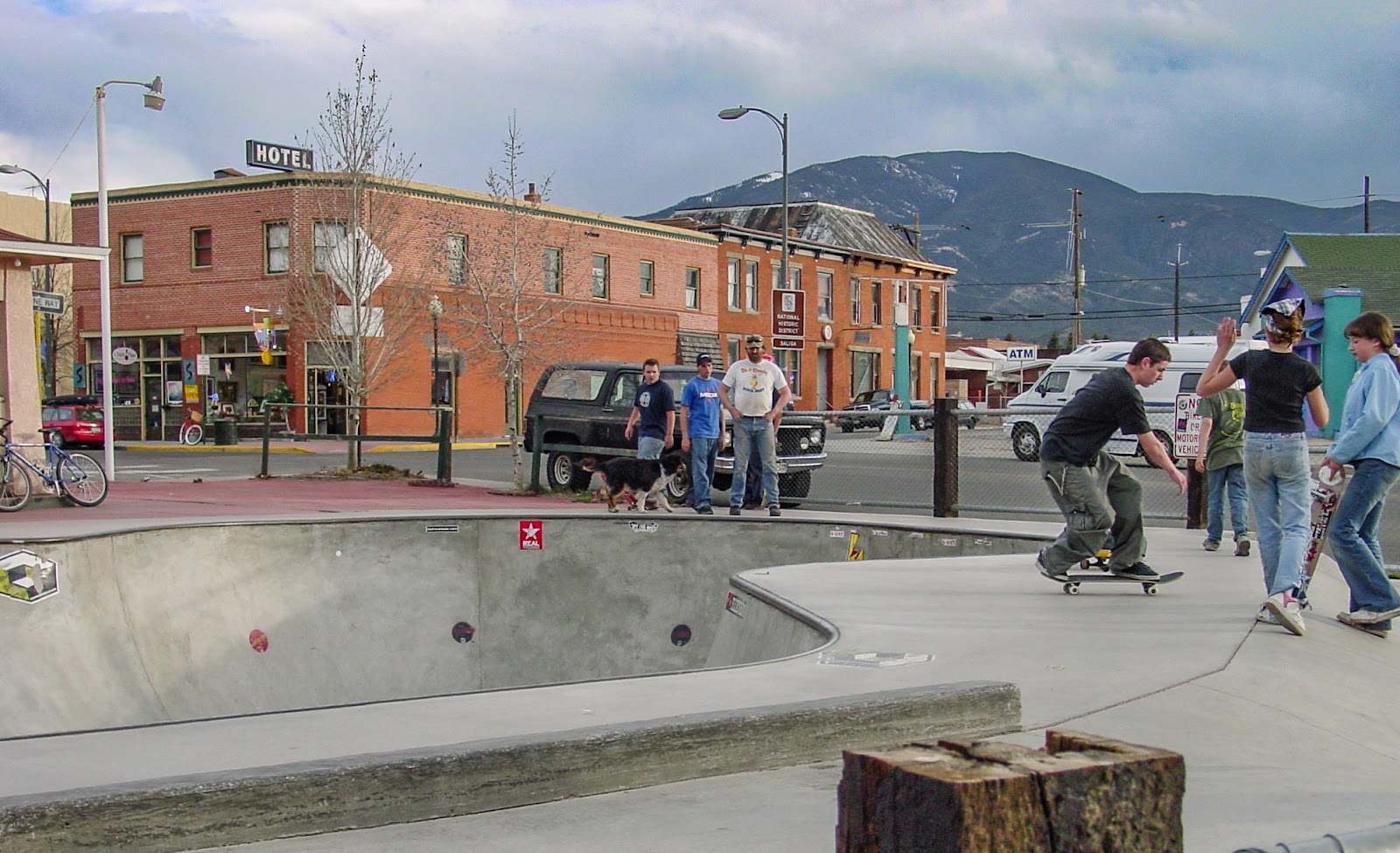 Young people watch one skater on the edge of a skatepark.