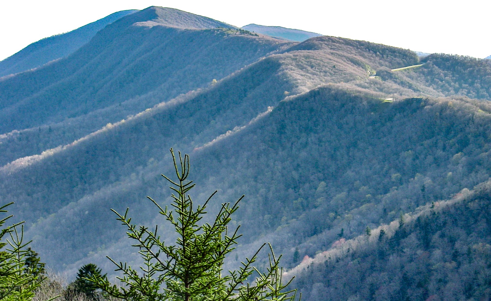 The spine of high peaks curves to the bright white sky. 