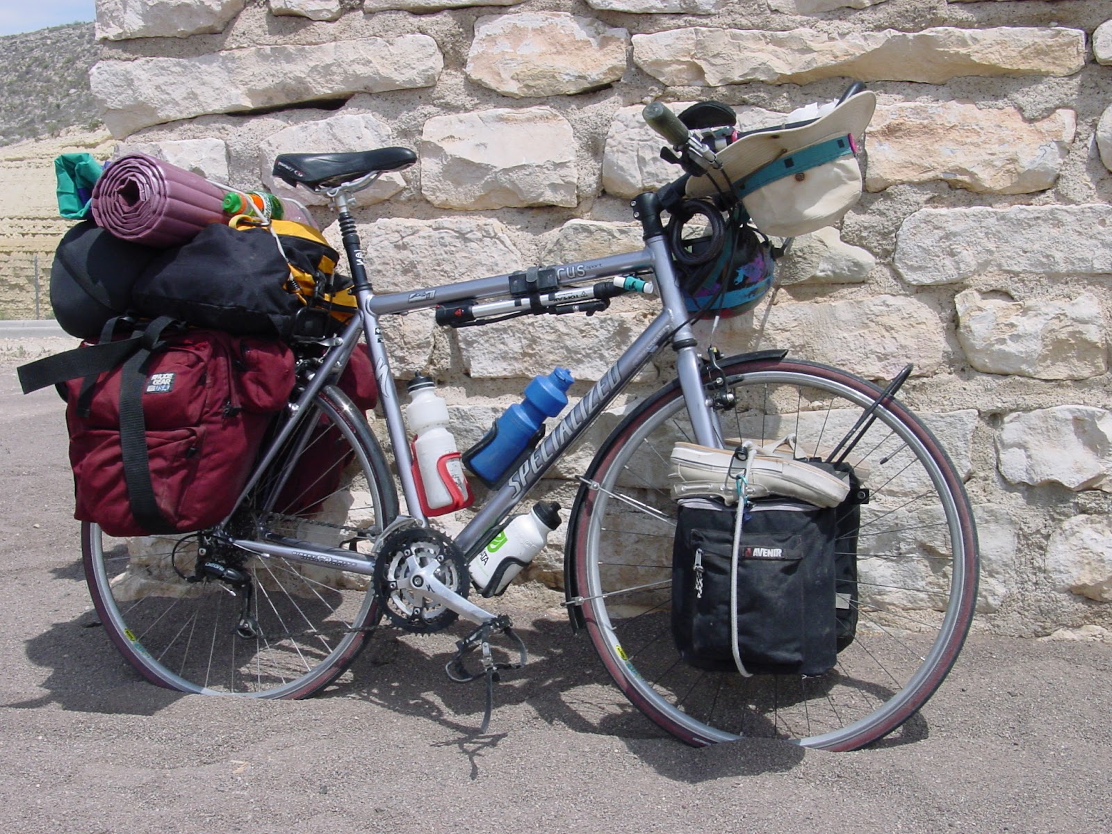 Bicycle loaded with camping gear leaning on an adobe brick wall.