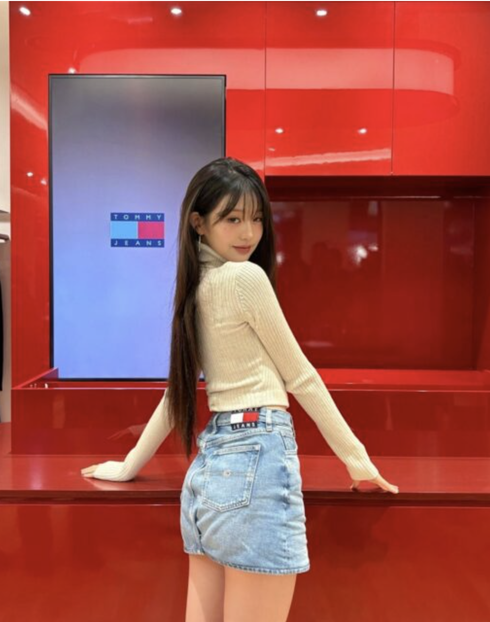 Wonyoung  at the Tommy Hilfiger event wearing a light brown long sleeve sweater and a short jean skirt. 