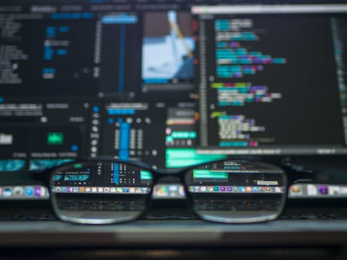 Free Eyeglasses reflecting computer code on a monitor, ideal for technology and programming themes. Stock Photo