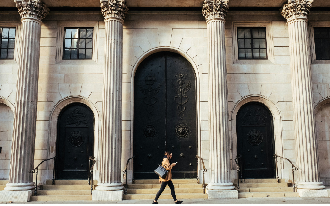 A person walking in front of a buildingDescription automatically generated