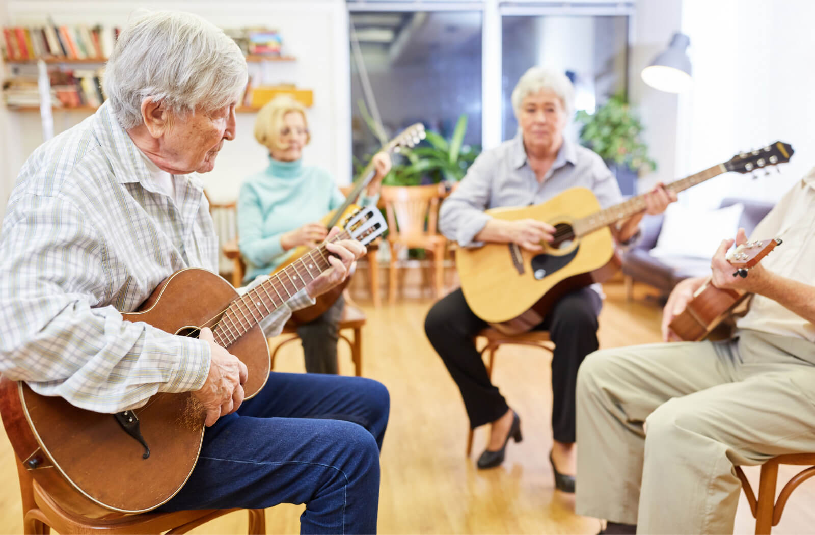 Seniors joyfully strum guitars in a music room, creating a harmonious atmosphere filled with the melodies of their shared musical expressions.