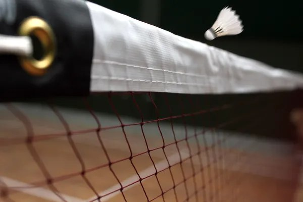 Ein Federball fliegt durch ein Badmintonnetz  