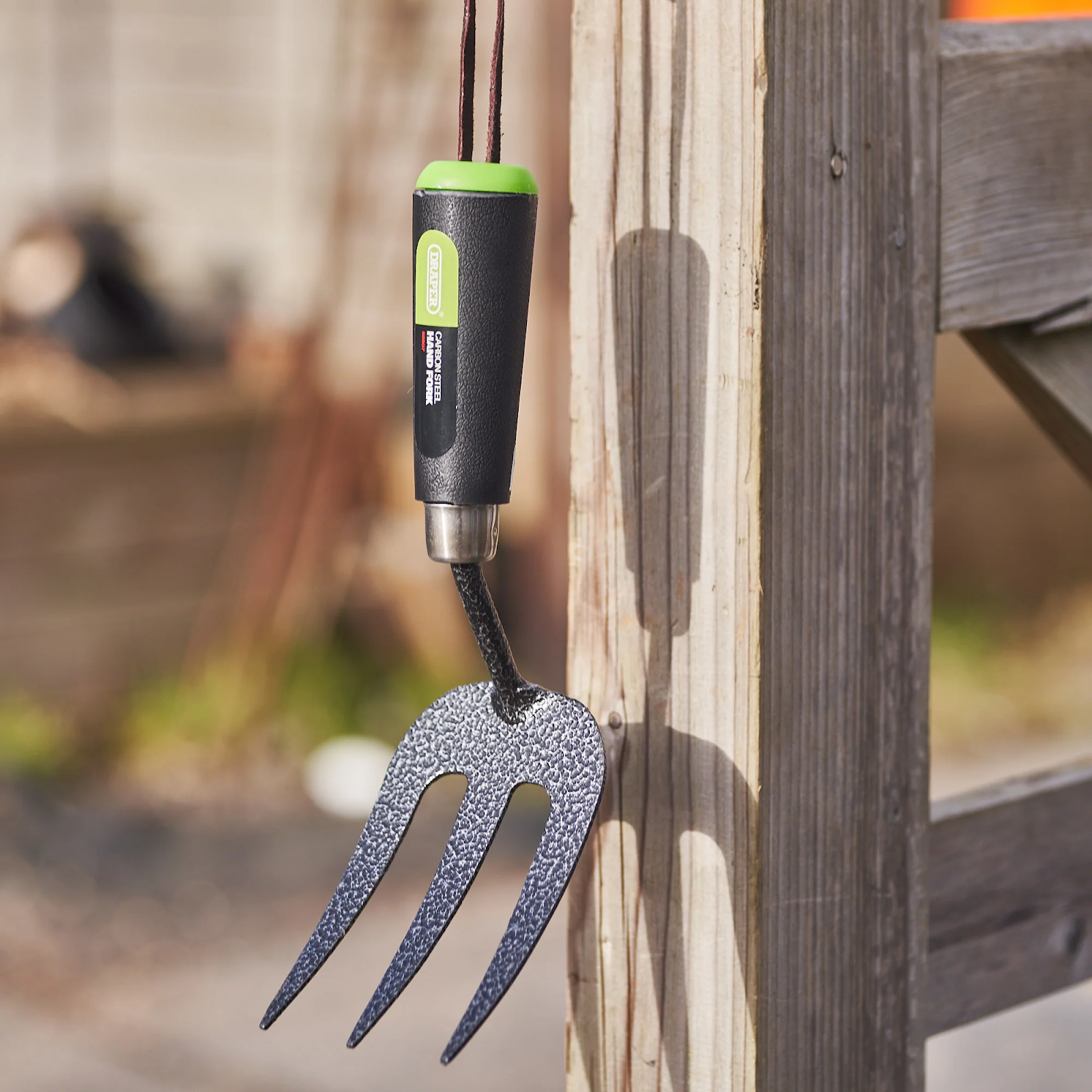 A garden fork hanging on a wood. It is one of the basic essential garden tools every gardener must have