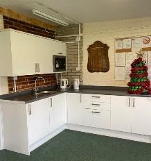 A kitchen with white cabinets and a brick wall Description automatically generated