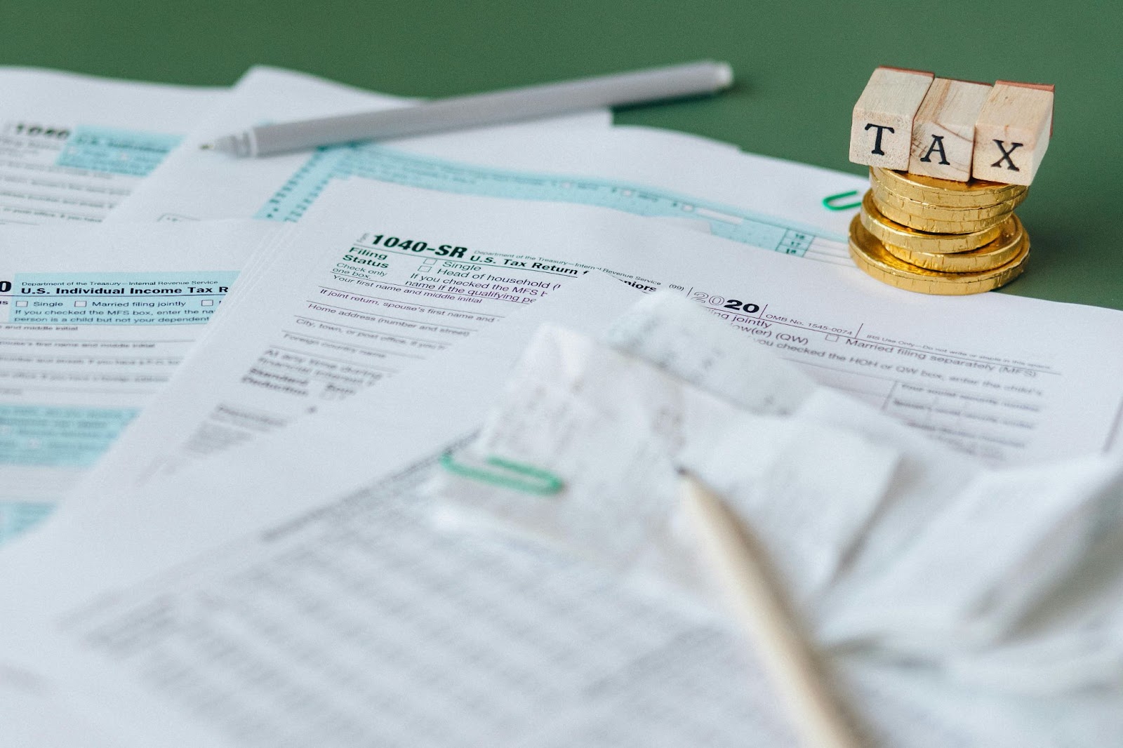 tax forms, calculator, and stacked coins labeled 'TAX' on green background