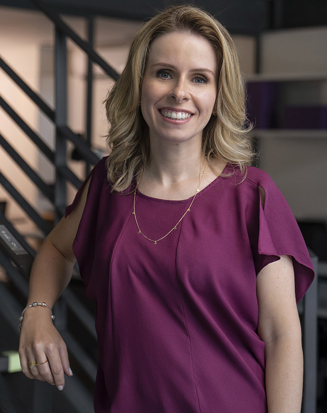 Livia Chanes, CEO da Nubank, usando uma blusa roxa e sorrindo para a camera. 