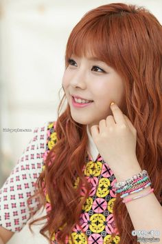 A photo of Singer Juniel placing her finger on her cheek