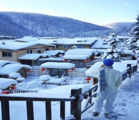 A person standing on a porch in a snowy town  Description automatically generated