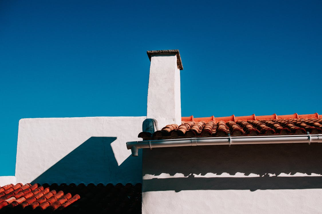 Close-up of a white house’s roofline featuring clean, well-maintained gutters, emphasizing proper exterior upkeep.