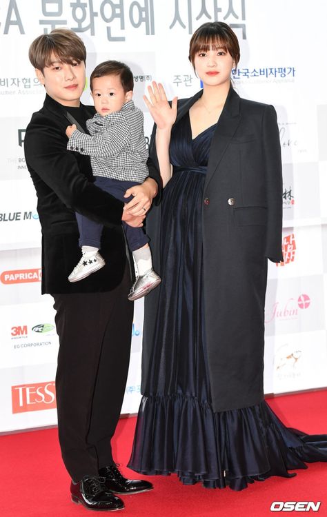 A picture of Yulhee and FTISLAND's Choi Minhwan and their baby on a black outfit 