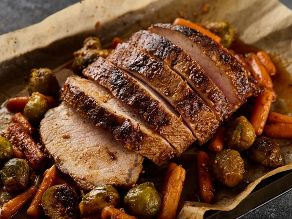 A perfectly roasted deli-style roast beef, sliced and served with tender Brussels sprouts and carrots on parchment paper
