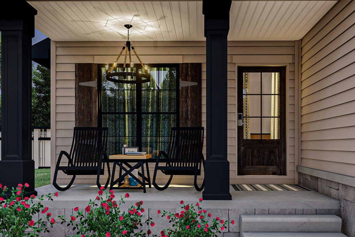 A closer look at the covered entry porch showing the black rockers and a small coffee table well-lit by a round chandelier.