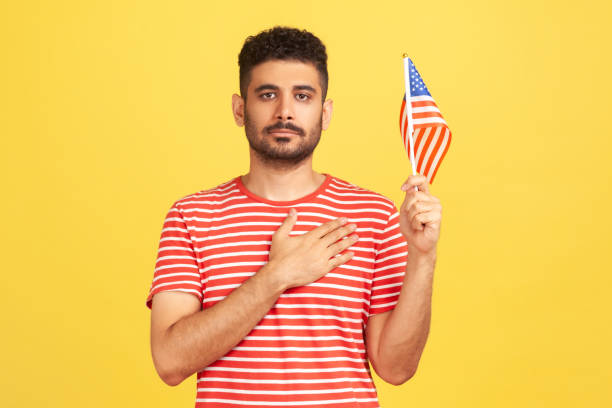 Hispanic man putting his right hand on his heart during naturalization oath with an American flag