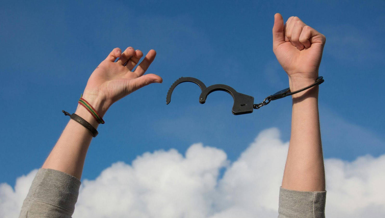 Two hands breaking free from a handcuff