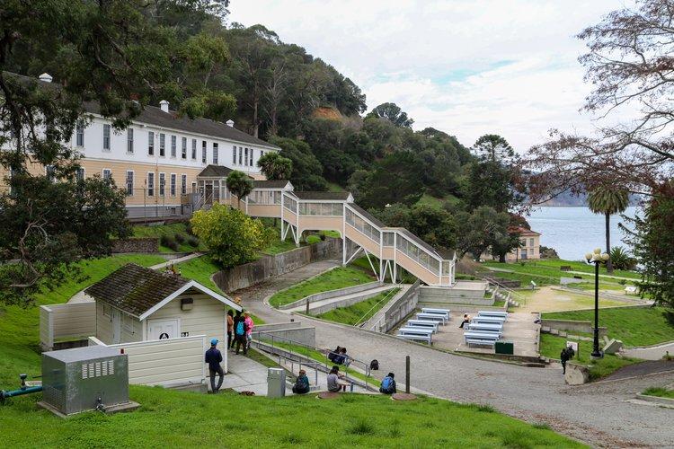 A group of people walking down a hill with stairs and stairs leading to a building  AI-generated content may be incorrect.