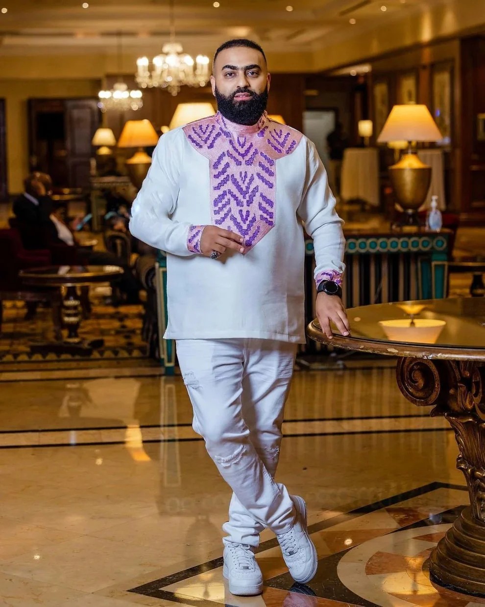 Man wearing a modern Habesha dress shirt with traditional purple embroidery, combining cultural style and everyday comfort for diaspora