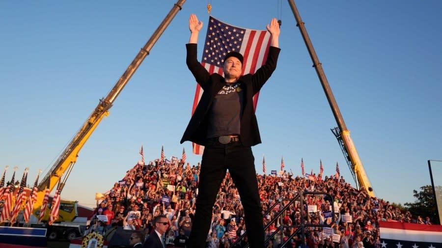 A person standing on a stage with a flag in the air

Description automatically generated