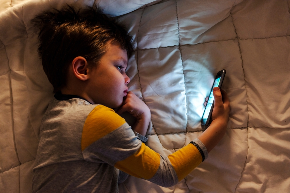 Boy holds his phone. Credit / Shutterstock