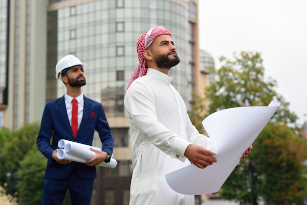 saudi businessman going through the building plan with his architect waiting on the