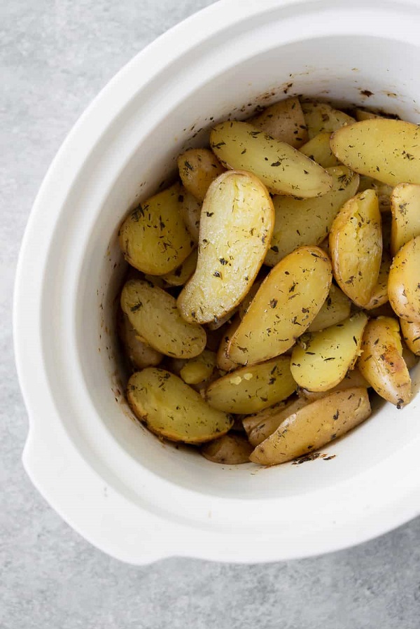 Slow-cooker garlic herb potatoes in a white serving bowl