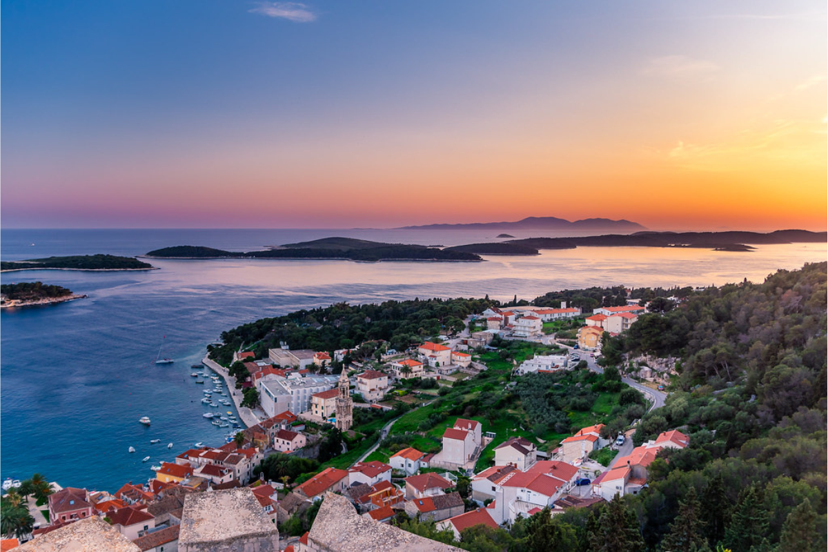 It's sunset time and sky displays various colors and clean and crystal water and group of houses near the water