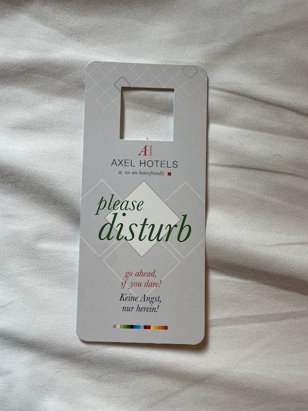 the please disturb door knocker sign for axel hotel berlin germany location laid out on a white bed sheet