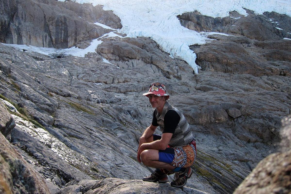 Wide shot photo of Dave Vass crouched on a rocky mountain side moments before his accident.