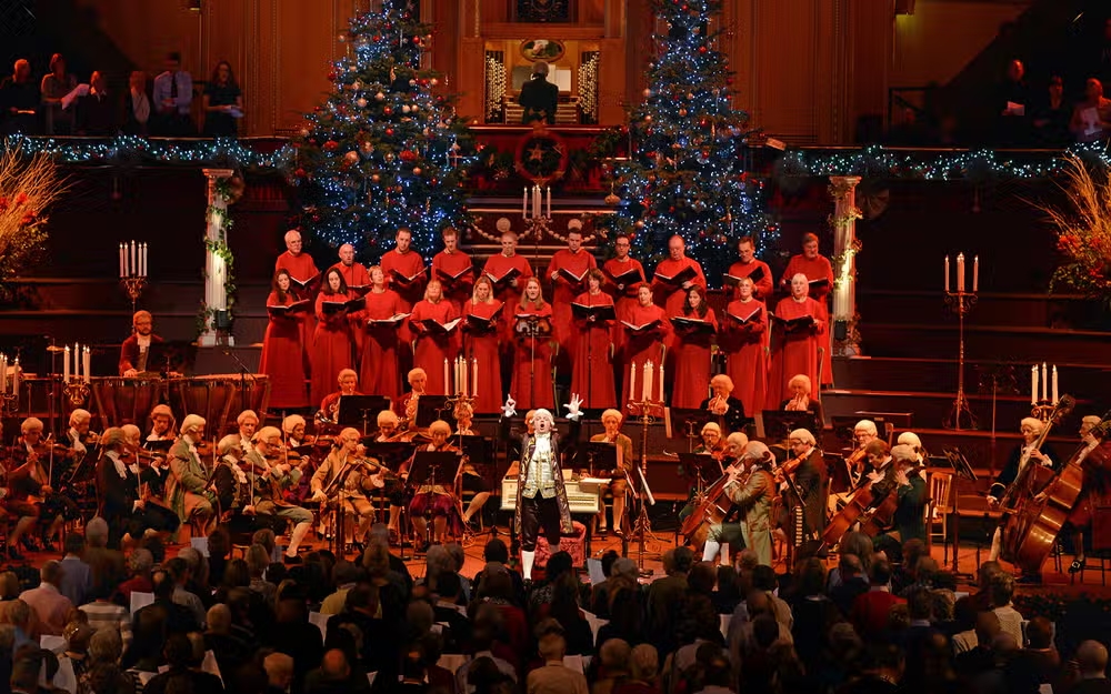 A group of carolers performing Christmas songs at a free Christmas carol service in London, surrounded by festive decorations