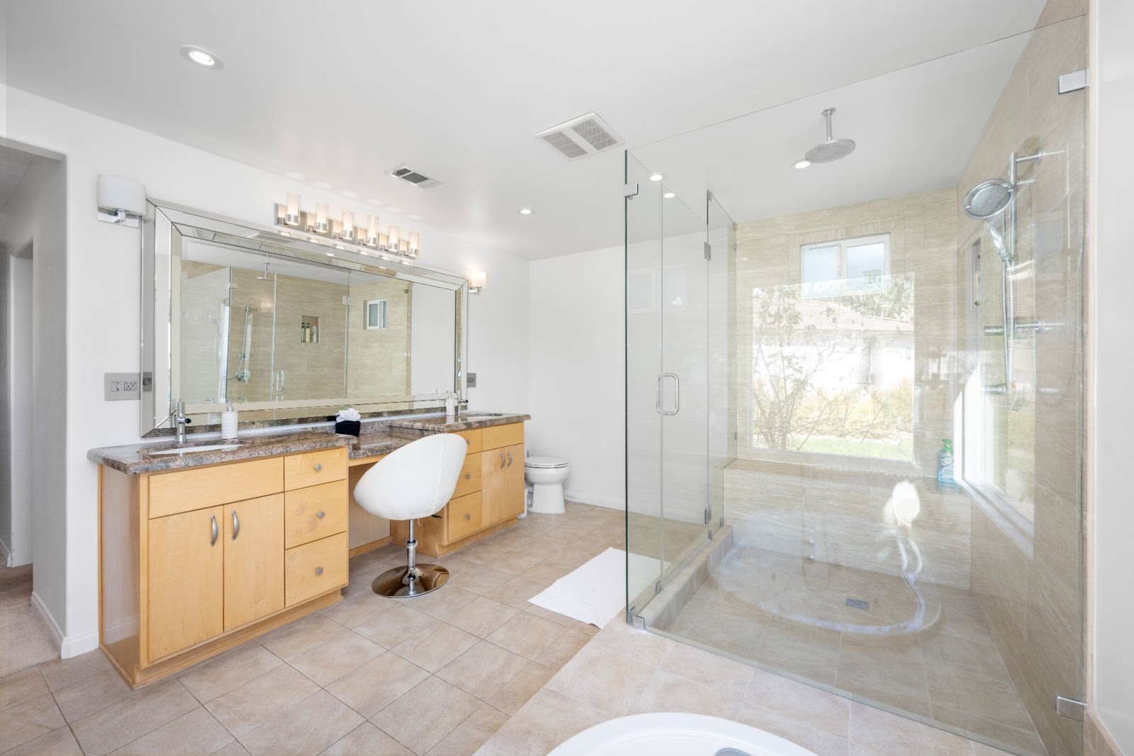 A spacious bathroom featuring a walk-in shower, a separate toilet and bathtub, and a dresser with wooden cabinets, offering both functionality and luxury.