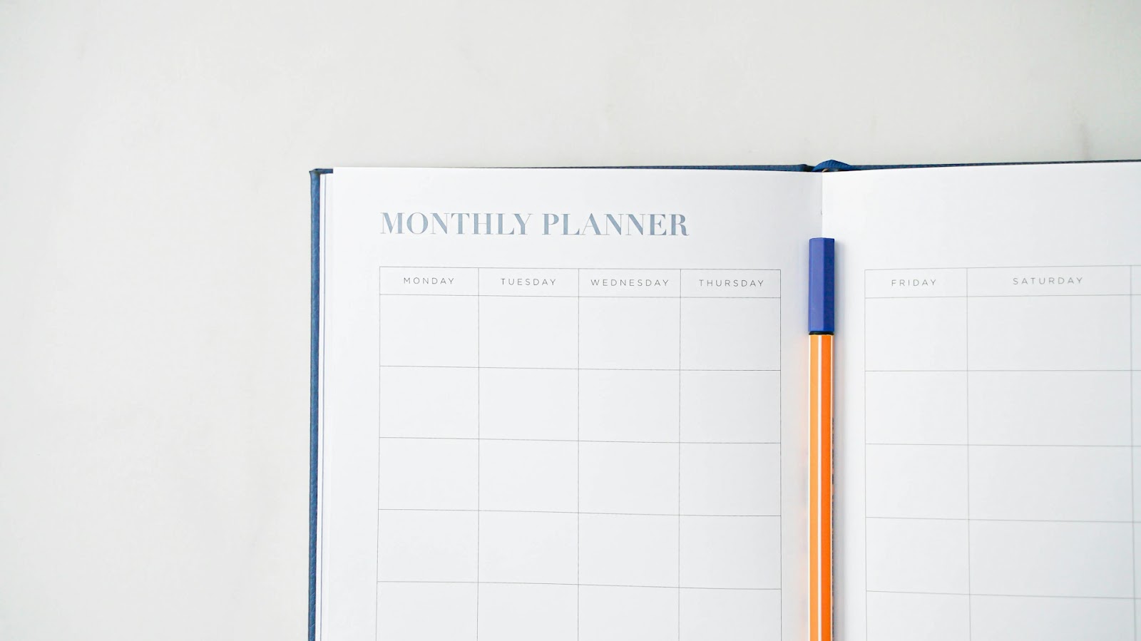 An image of a Montly Planner Book with a pen