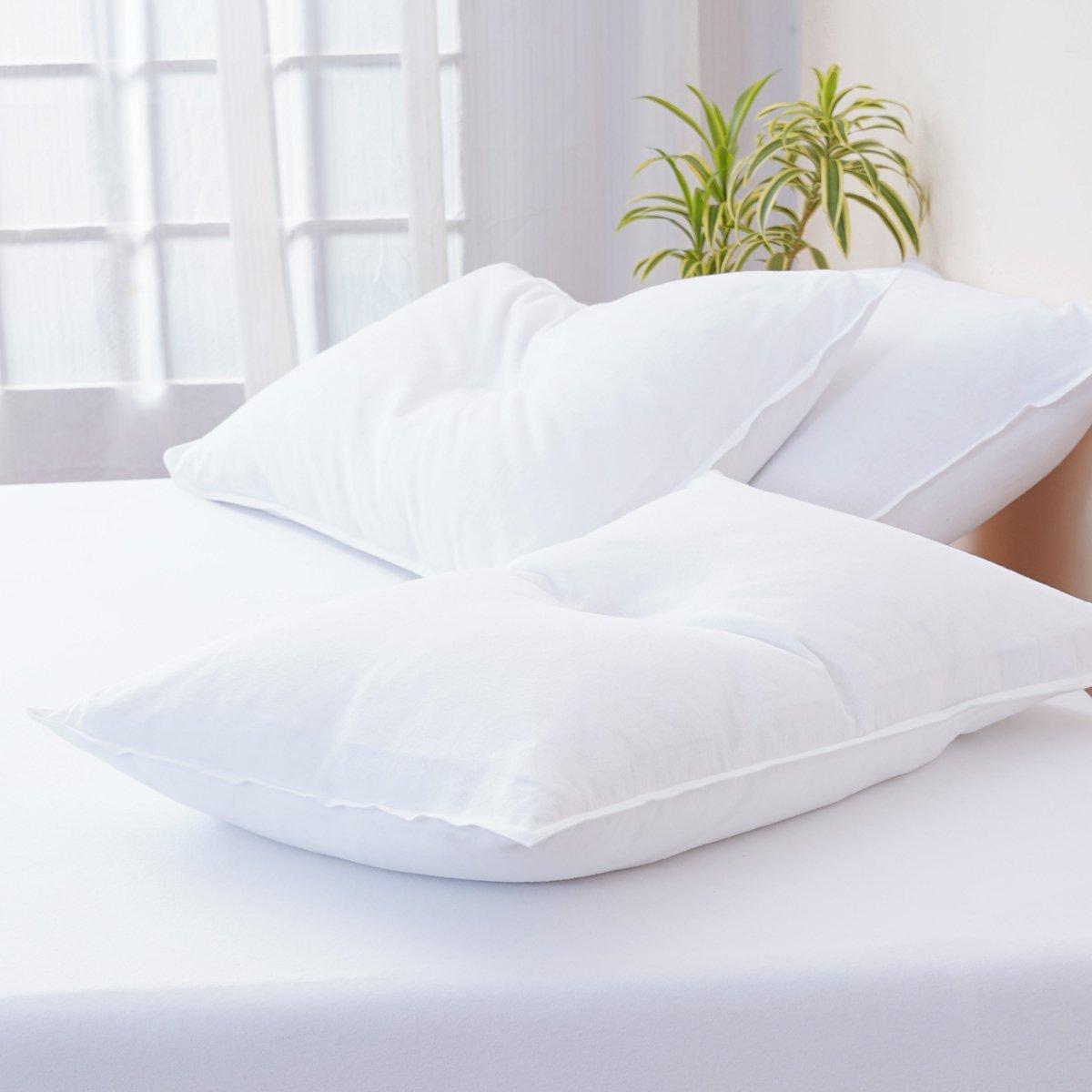 A bed with white pillows and a plant