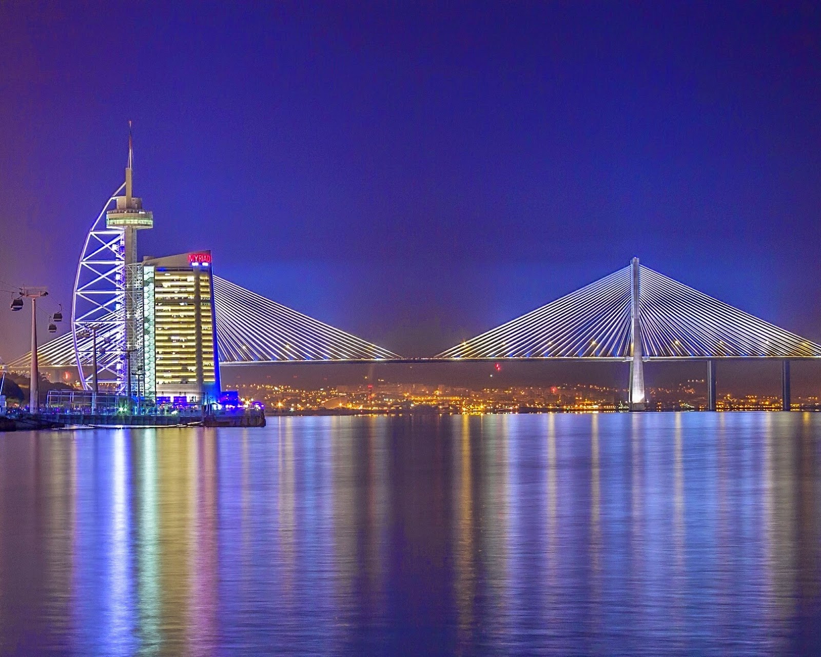 Bridge with lights reflecting on the water below.